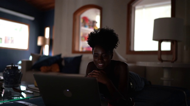 年轻女性在家用笔记本电脑看电影视频下载