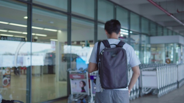 带着行李走过机场航站楼的亚洲男子视频素材