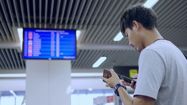 带着行李通过走廊过境，同时使用手机的男子旅客视频素材