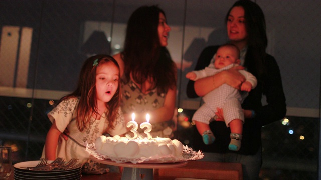正宗的生日庆祝，家庭成员唱生日歌，吹蜡烛在蛋糕上视频下载