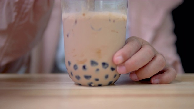 用塑料吸管在桌上搅拌台湾奶茶。视频下载