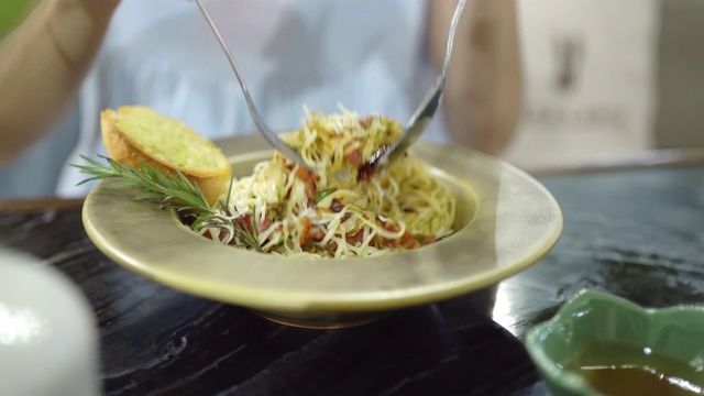 人的手拿着意大利面在餐厅里吃。视频素材