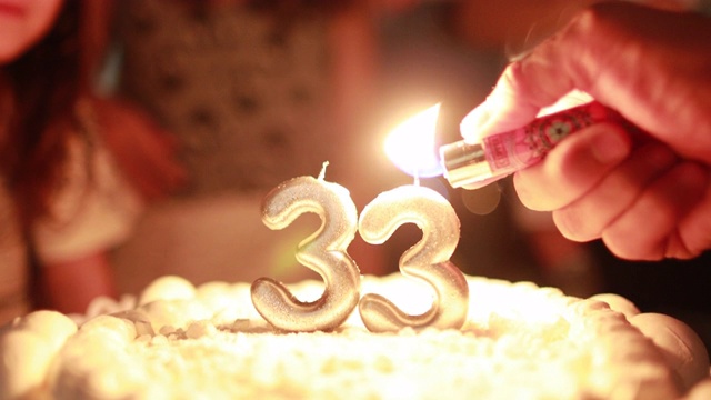特写手点燃生日蛋糕蜡烛与打火机庆祝33岁视频下载