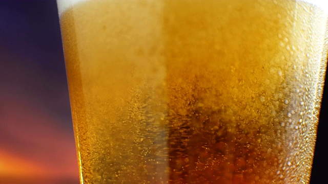 啤酒玻璃特写。在一杯啤酒泡沫和气泡在慢动作。在一杯啤酒泡沫和气泡在慢动作。啤酒杯特写视频素材