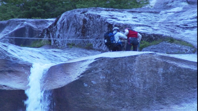 登山队在瀑布附近用绳降。视频素材