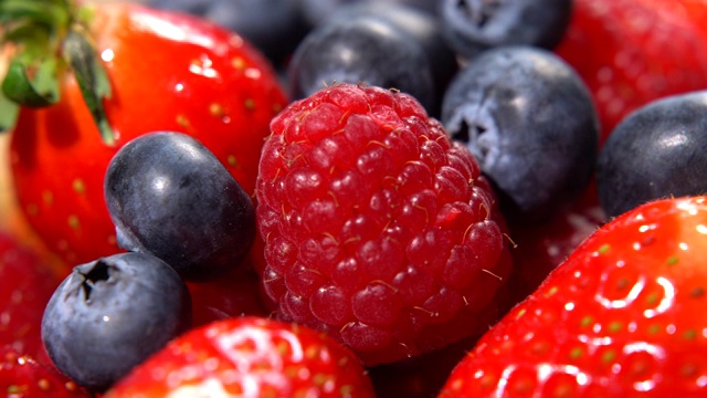 近距离拍摄成熟的红色草莓和下落的黑莓。惊人的健康营养特性，人体有机体的完整维生素复合体。美味的果园，美味的浆果概念视频下载