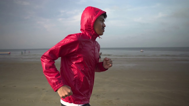 戴着兜帽在沙滩上跑步的男人视频下载