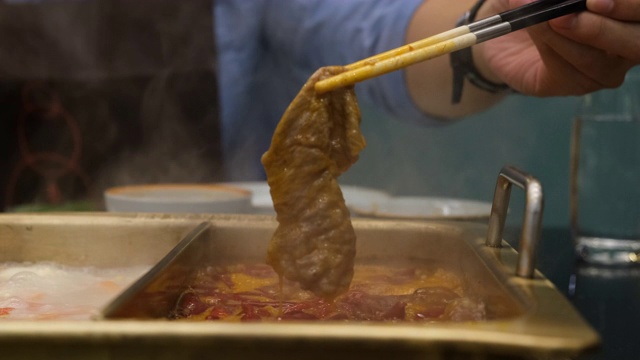用筷子切成薄片的牛肉在热辣的红辣椒汤中沸腾，被称为“涮锅涮锅马拉”，牛肉就在汤中浸泡一下。中国著名的美味食物。视频素材