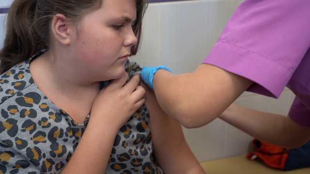 医生给少女接种疫苗。接种疫苗期间的少女。肩部中枪。特写镜头。视频素材