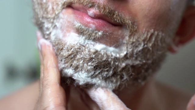 新鲜芳香男士剃须香波。干刺胡子用凝胶洗涤剂，早上在镜子前护肤程序。英俊的男人把洗发水倒在手上，给没刮干净的胡子擦洗。剃须前用软化香波视频素材