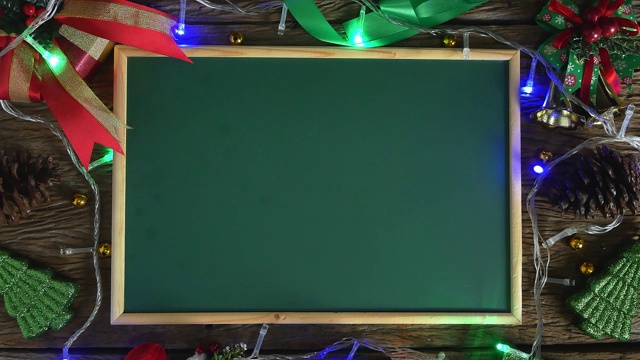 空的绿色板放在用圣诞装饰品装饰的木桌上。俯视图视频下载
