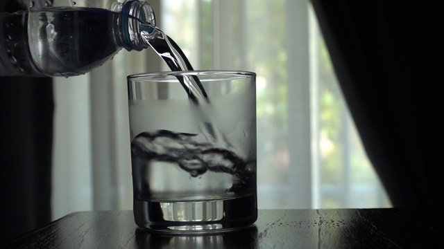 用手将饮用水倒入玻璃杯中视频素材