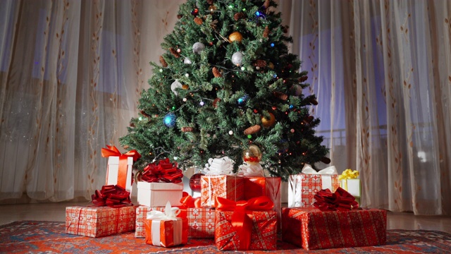 圣诞树上闪烁着圣诞花环，新年快乐，圣诞快乐。冬天的装饰品和家里的装饰。圣诞礼品盒躺在树下。神奇的冬夜，圣诞庆祝的火花视频素材