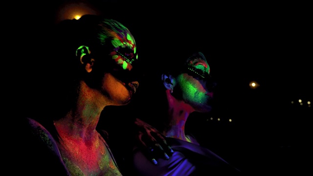 两个女人与发光的荧光身体艺术看着相机视频素材