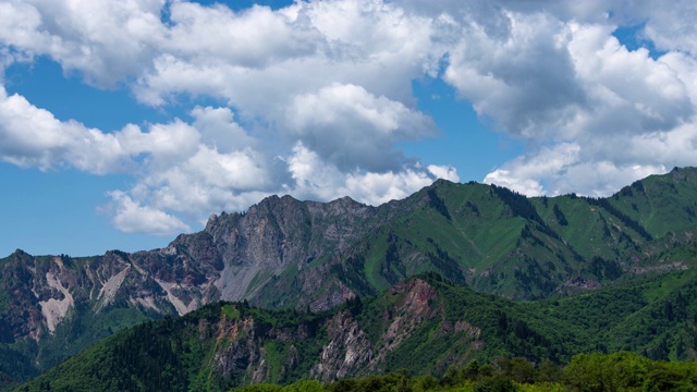 在吉尔吉斯斯坦Sary-Chelek附近的绿色山脉上空的云的时间流逝视频下载