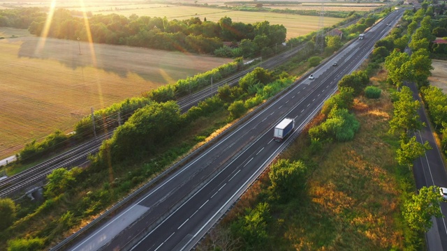无人机拍摄:意大利农村地区繁忙的高速公路上行驶的长途半挂卡车。背景中的农田和山丘视频下载