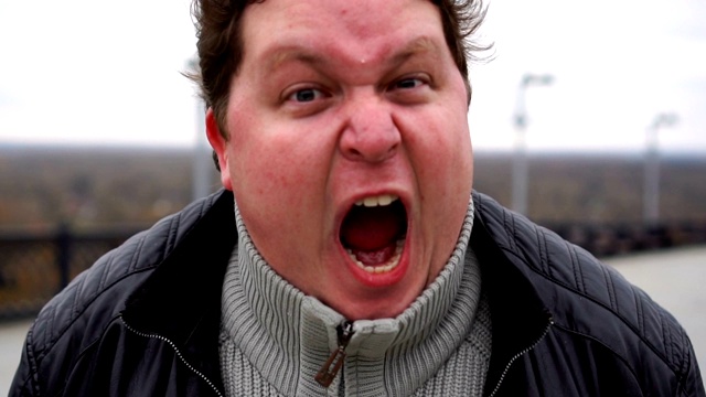 放大肖像的肥胖愤怒的人看着相机和尖叫。视频下载