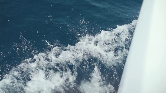 美丽的白色游艇破浪，慢镜头拍摄。湛蓝的水。浪花溅起的水花向不同的方向爆炸视频素材