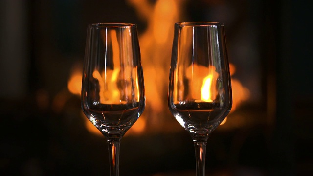背景是壁炉前的香槟。完美的浪漫夜晚-特写-饮酒和情侣概念视频下载