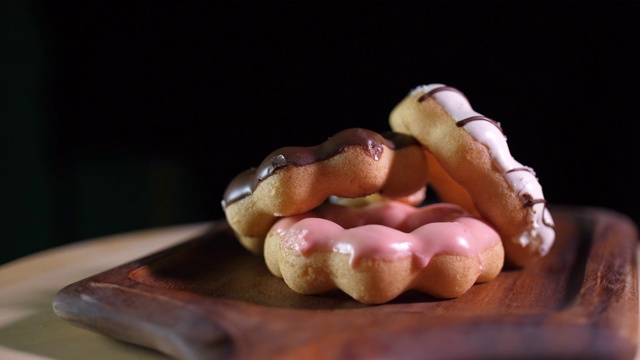 旋转拍摄的甜甜圈在木托盘与黑暗的背景视频素材