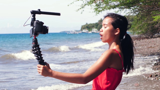 一名亚洲女博主对着拍摄社交媒体内容的摄像机说话。视频素材