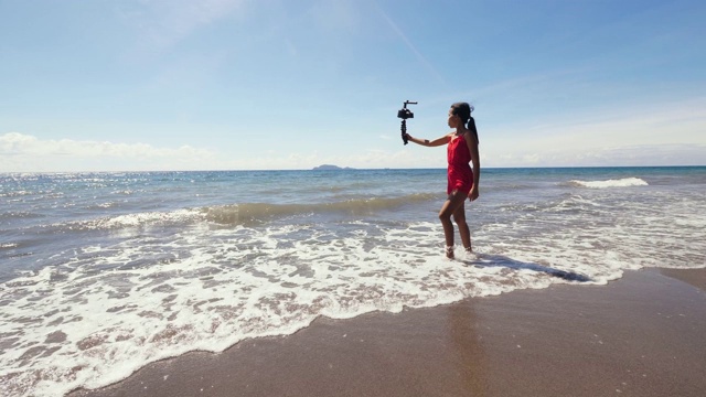 旅游视频博主在夏天度假时在海滩上录制视频。视频素材