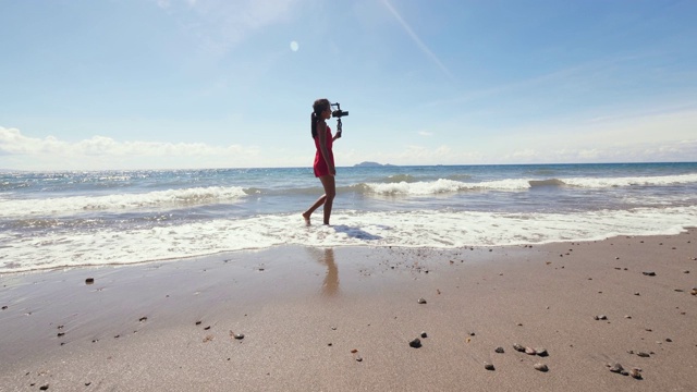 亚洲女性视频博主走在海滩上，并为旅游视频博主录制视频。视频素材