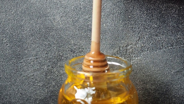 金色的液体蜂蜜从棍子流进一个玻璃罐视频素材
