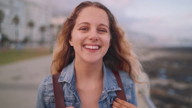 一个年轻迷人的微笑女人的肖像在城市街道上感到快乐，看着相机视频素材