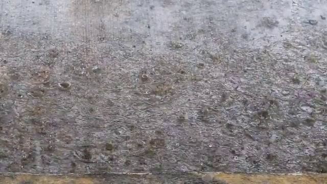 雨开始滴在灰色的混凝土路面，混凝土的墙壁纹理。水泥表面视频素材