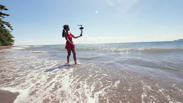 一位千禧一代的视频博主在海滩上散步，并为社交媒体录制视频视频素材