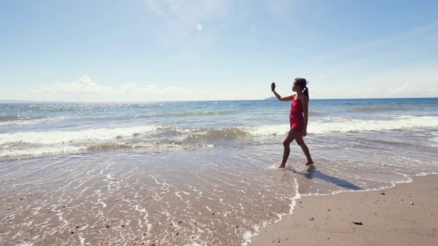 亚洲的视频博主在夏天用智能手机在海滩上拍摄视频博客视频素材