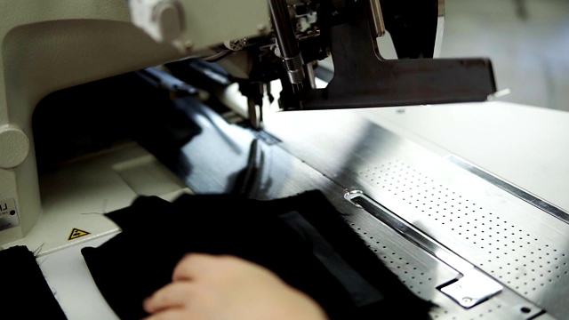 女性的手把黑色的纺织品到自动缝纫机缝纫直针。女人的手在缝纫机上用激光自动测量。时尚、创作和剪裁。慢动作视频素材