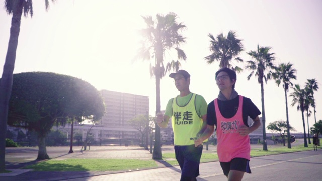 一个盲人马拉松运动员和他的向导跑步的跟踪镜头视频素材