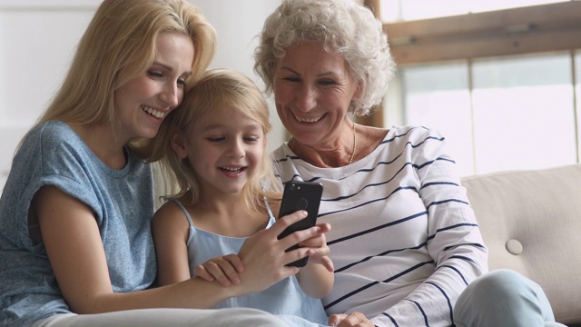 快乐的三个年龄的跨代女性家庭与手机的乐趣视频素材
