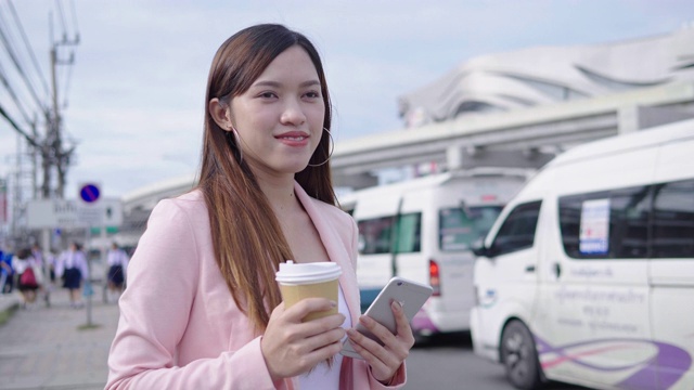一名女子在城市里一边用智能手机一边等出租车视频下载