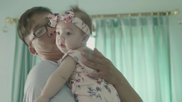 父亲在客厅里抱着宝宝，用鼻子爱抚视频素材