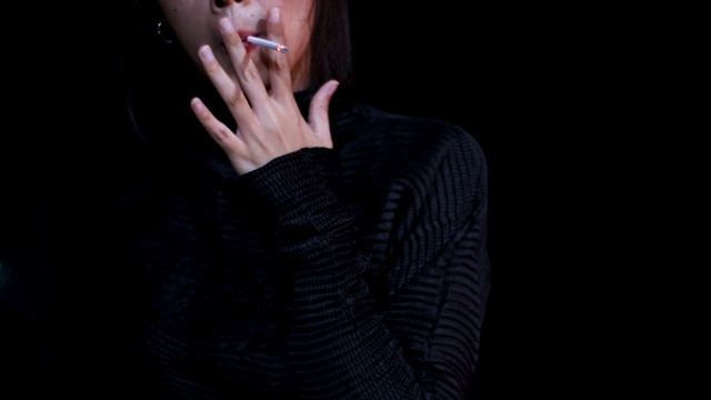 4k年轻亚洲女人穿着黑色长袖毛衣站在阳台外抽烟，孤独的心情，紧张的焦虑，担心，夜晚外出，夜景，温暖的光，影子和光，视频素材