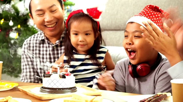 快乐亚洲一家在客厅唱生日歌，给女儿送礼物视频素材