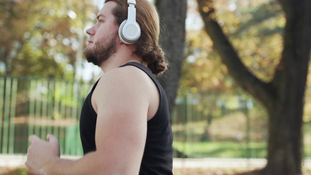 一个帅哥运动员的肖像，拿着手机，穿着运动服，在外面跑步。理念:热爱运动，健康生活方式，美丽，肌肉，快乐，燃烧卡路里。视频素材