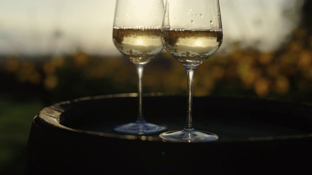 日落时分，木桶上放两杯白葡萄酒视频素材