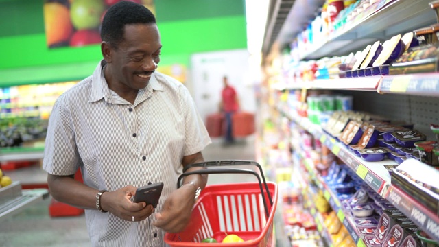 成熟的男人在超市购物，用智能手机扫描条形码视频素材