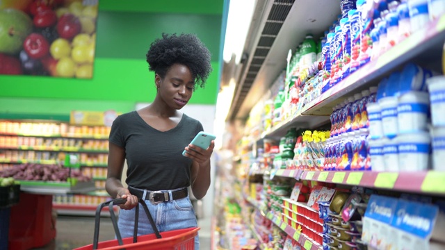 年轻女子在超市使用手机选购商品视频素材
