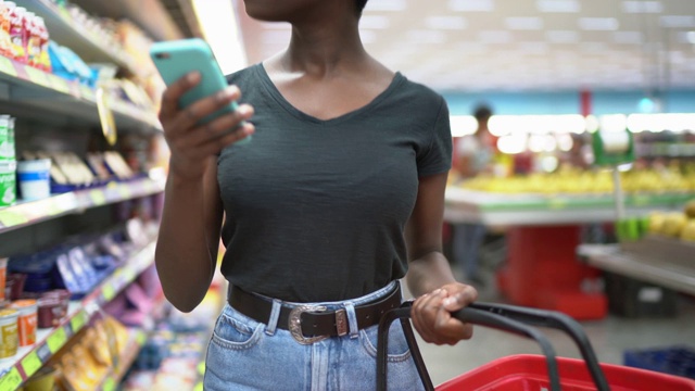 年轻女子在超市使用手机选购商品视频素材