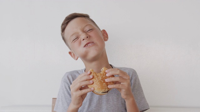 快乐的男孩吃着美味的快餐汉堡视频素材