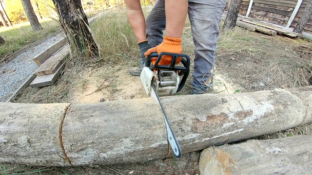 一个男人正在用手持式链锯锯木头。视频素材