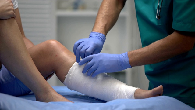 专业外科医生在女性病人腿上涂抹石膏，外伤，医疗保健视频下载