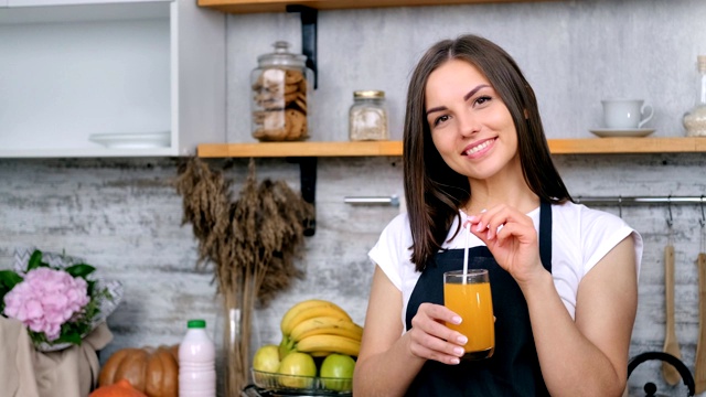 肖像美丽微笑的女孩摆姿势举着一杯新鲜的维生素橙汁中等近距离视频素材