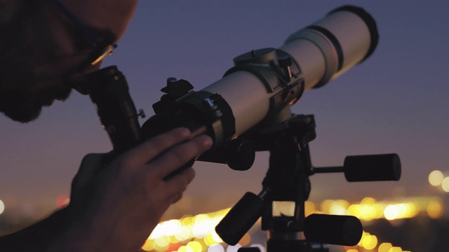 人们在城市周围用天文望远镜看天空。视频下载