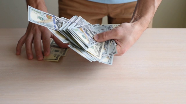 男人的手在桌子上耙了一堆钞票。贪婪的概念视频素材